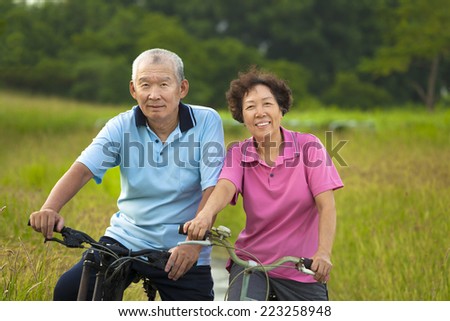 Happy Asian seniors couple biking in Park. retirement and health concept