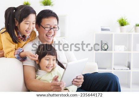 happy father using tablet pc with little girls