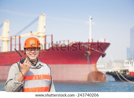 smiling dock worker holding  radio and  ship background