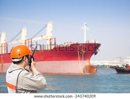 Harbor dock worker talking on  radio with ship background
