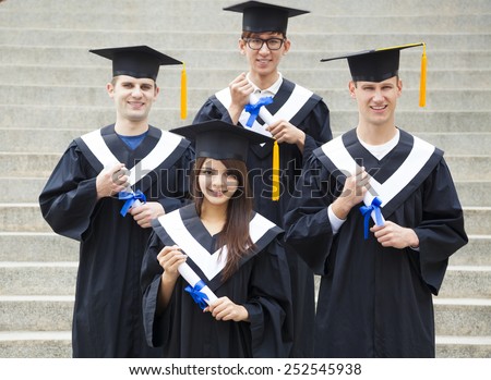 young students in graduation gowns on university campus