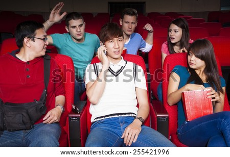 Young men talking on the phone while watching movie at the cinema