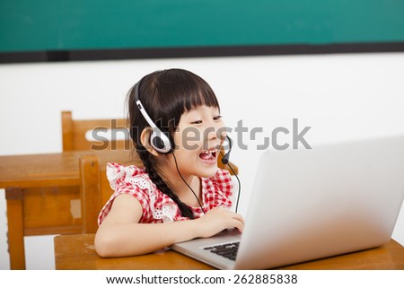 happy little girl learning computer in classroom