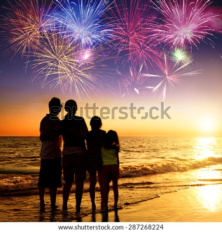 happy family watching the sunset and firework on the beach