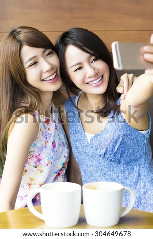 happy girlfriends taking a selfie in coffee shop