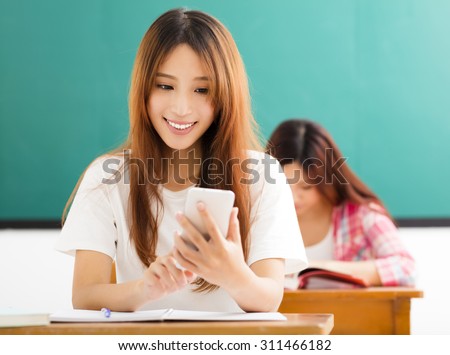young female student using smart phone in classroom