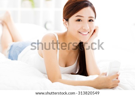 smiling young woman with smart phone on the bed