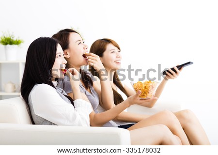 happy young woman group  eating snacks and watching the tv
