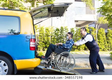 driver helping man on wheelchair getting into taxi