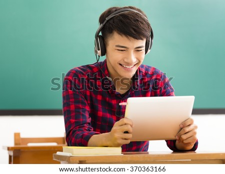 happy student reading tablet in classroom