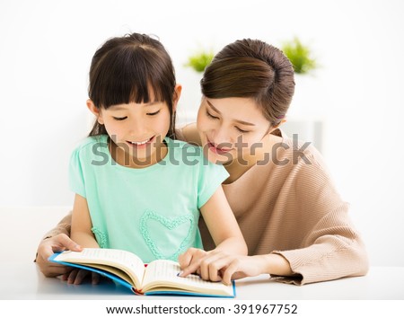 happy Little girl looking at book  with her mother