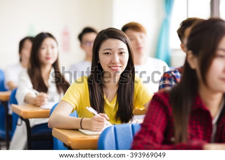 smiling female college student sitting  with classmates