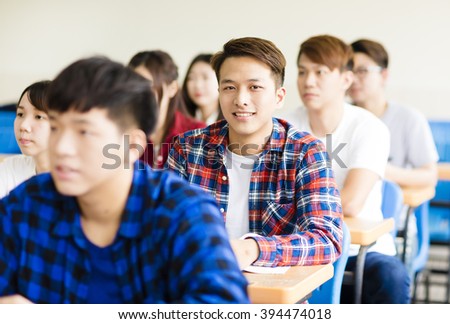 smiling male college student sitting  with classmates