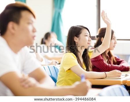 female college student raise hand for question in classroom