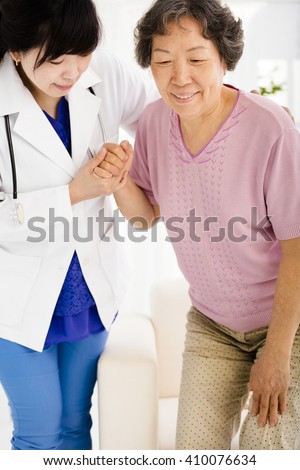Nurse in nursing home helping senior woman stand up