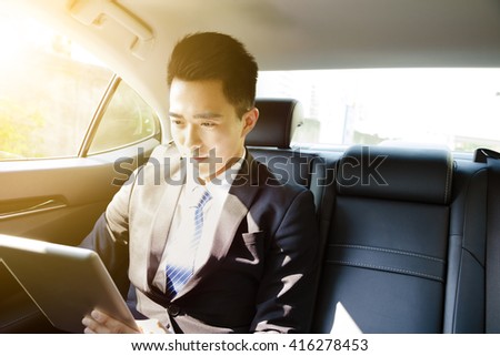 young businessman using tablet pc in car at morning