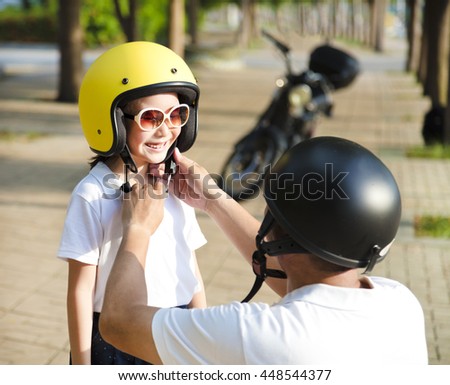 father trying to wear a bike helmet to his daughter
