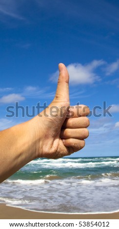 thumb up hand sign with beach background