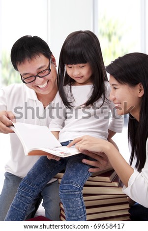 Happy asian family studying together. Parent helping daughter  reading book