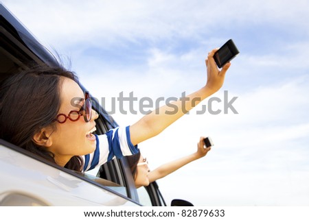 happy young woman  holding camera and mobile phone taking photos in the car