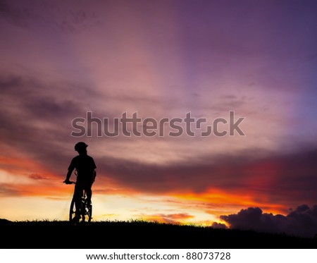 The silhouette of mountain bicycle rider on the hill with beautiful sunrise background