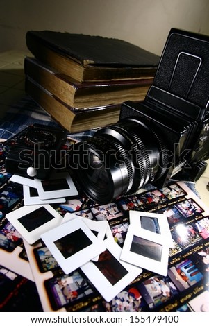 Retro Medium Format Film Camera and Paraphernalia. A photo of a retro medium format film camera with contact sheets, slide films, light meter and books.