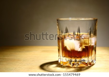 Alcoholic Drink in a Glass with Ice A photo of an alcoholic drink or liquor with ice in a glass and on a table