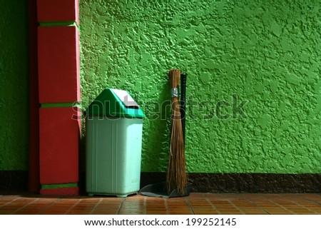 Trash bin, broom and dust pan Photo of a trash bin, a broom and a dust pan in an empty garage