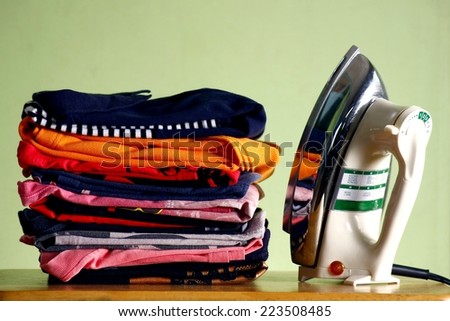 stack or pile of ironed and folded shirts and an iron