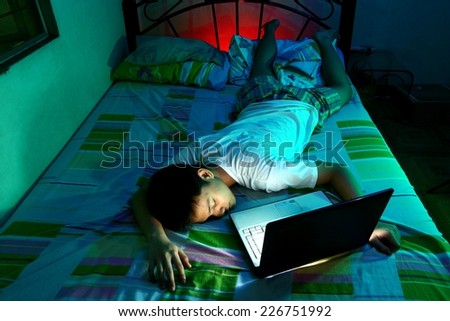 Young Teen sleeping front of a laptop computer and on a bed Photo of a Young Teen sleeping in front of a laptop computer and on a bed