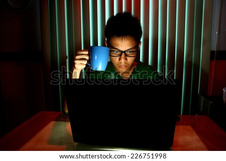 Young Teen holding a coffee mug in front of a laptop computer Photo of a Young Teen holding a coffee mug in front of a laptop computer