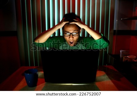 Young Teen with eyeglasses acting surprised in front of a laptop computer Photo of a Young Teen with eyeglasses acting surprised in front of a laptop computer