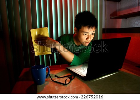 Young Teen holding a book in front of a laptop computer Photo of a Young Teen holding a book in front of a laptop computer