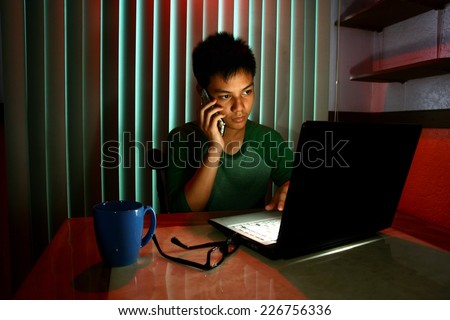 Young Teen using a cellphone or smartphone in front of a laptop computer Photo of a Young Teen using a cellphone or smartphone in front of a laptop computer