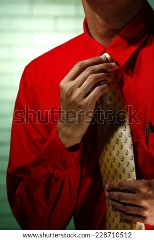 Man wearing red long sleeve shirt and yellow necktie Photo of a man wearing red long sleeve polo shirt and holding his yellow necktie