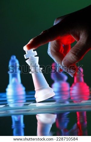 Finger tilting a chess piece on Chess Board Photo of a Finger tilting a chess piece on Chess Board