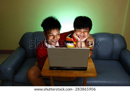 Two Young boys using a laptop computer and smiling Photo of two Young boys using a laptop computer and smiling