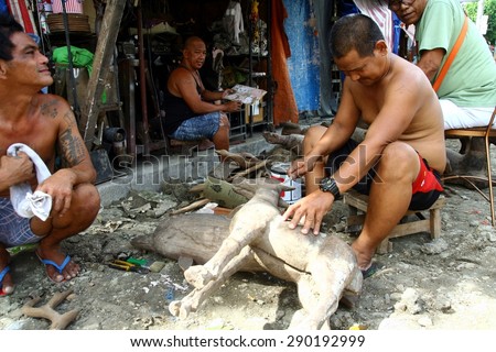 MANILA, PHILIPPINES - JUNE 22, 2015: Wood carvers puts finishing touches on an ornamental figurine sold at a flea market called Dapitan Arcade.