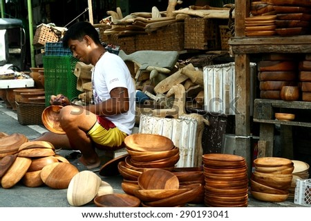 MANILA, PHILIPPINES - JUNE 22, 2015: Wood carvers puts finishing touches on wooden plates sold at a flea market called Dapitan Arcade.