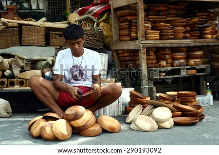MANILA, PHILIPPINES - JUNE 22, 2015: Wood carvers puts finishing touches on wooden plates sold at a flea market called Dapitan Arcade.