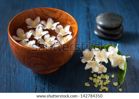 White flowers in a bowl, stones for massage and sea salt. Spa composition.
