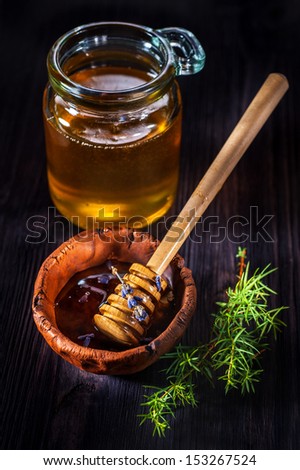 Pot of honey with lavender honey and stick on a wooden background