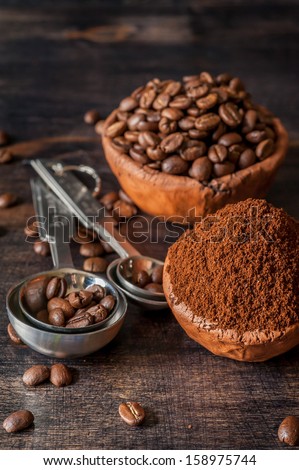 Ceramic bowls with coffee beans and ground coffee on a wooden background
