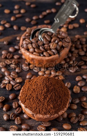Vintage bowls with coffee beans and ground coffee on a wooden board