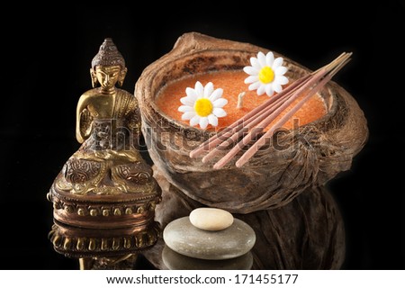 Spa. Buddha statue, stone massage and incense sticks on a black background