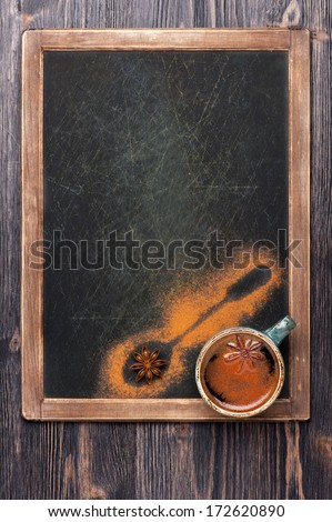 Cup of coffee with spices on vintage slate chalkboard. Design for the menu.
