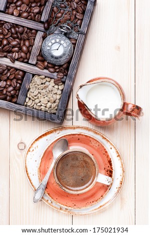 Cup of coffee with milk and  old box with coffee beans