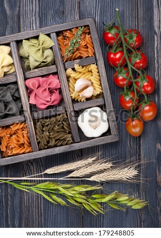 Various Italian pasta, cherry tomatoes, garlic in wooden vintage box