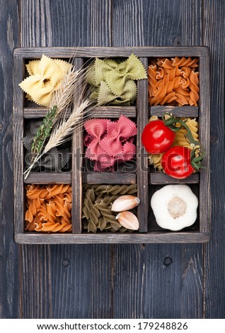 Various Italian pasta, cherry tomatoes in vintage wooden box