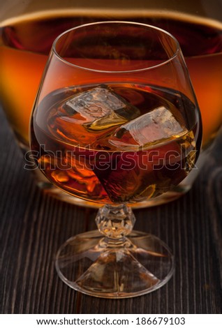 Whiskey with ice on dark wooden background